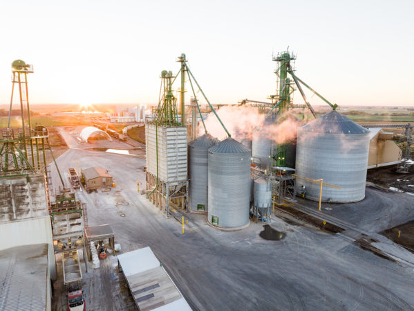 Aerial JDH Gooding, Idaho Mill. The sun is rising in the horizon and steam is coming off of the mills and silos.